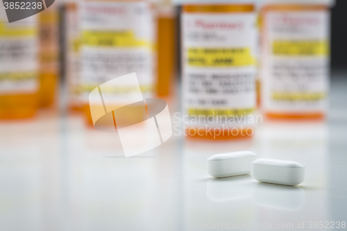 Image of Medicine Bottles and Pills on Reflective Surface With Grey Backg