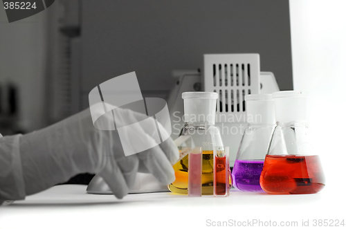 Image of hand holding laboratory flasks and computer mouse