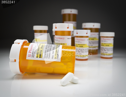 Image of Medicine Bottles and Pills on Reflective Surface With Grey Backg