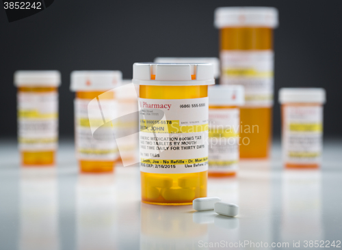Image of Medicine Bottles and Pills on Reflective Surface With Grey Backg