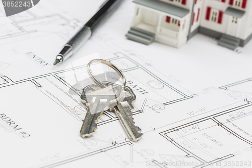 Image of Model Home, Engineer Pencil and Keys Resting on House Plans