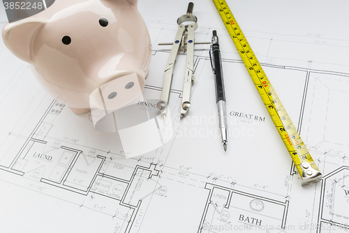 Image of Bank, Compass, Pencil and Measuring Tape Resting on House Plans