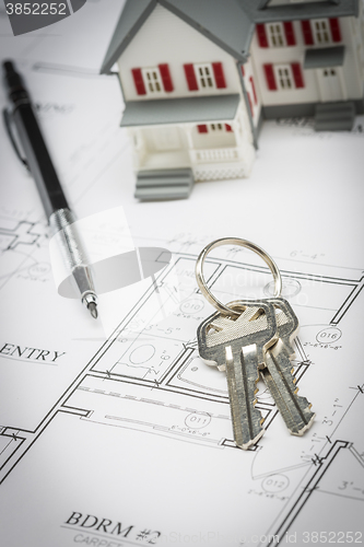 Image of Model Home, Pencil and Keys Resting On House Plans