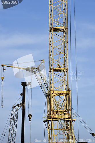 Image of Crane and building construction site against blue sky