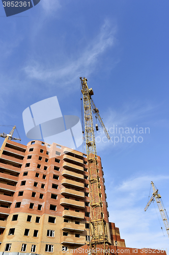 Image of Crane and building construction site against blue sky