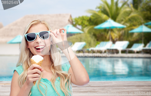 Image of happy woman in sunglasses with ice cream on beach