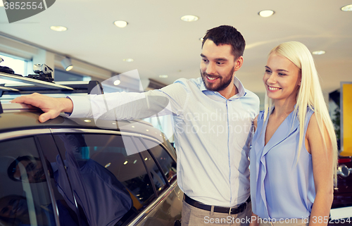 Image of happy couple buying car in auto show or salon