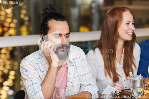 Image of man with smartphone and friends at restaurant