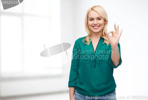 Image of smiling young woman in shirt showing ok hand sign