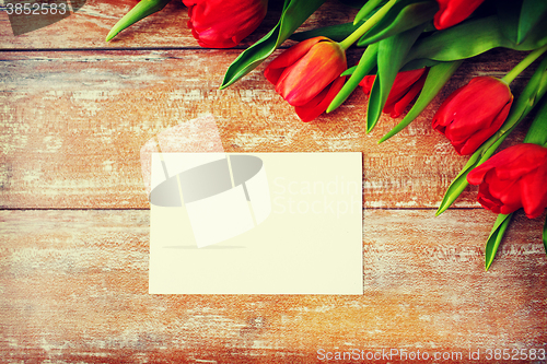 Image of close up of red tulips and blank paper or letter