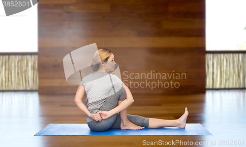 Image of woman making yoga in twist pose on mat