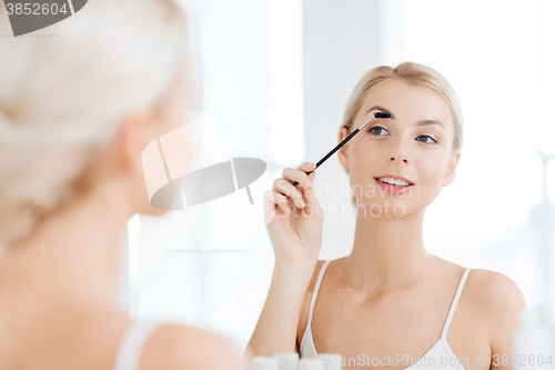 Image of woman brushing eyebrow with brush at bathroom