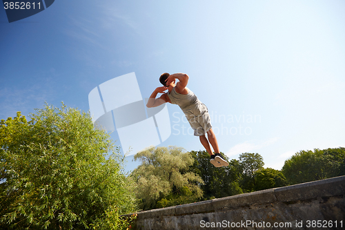 Image of sporty young man jumping in summer park