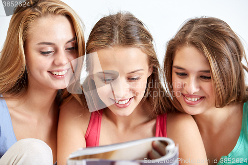 Image of friends or teen girls reading magazine at home