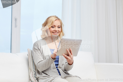 Image of happy middle aged woman with tablet pc at home