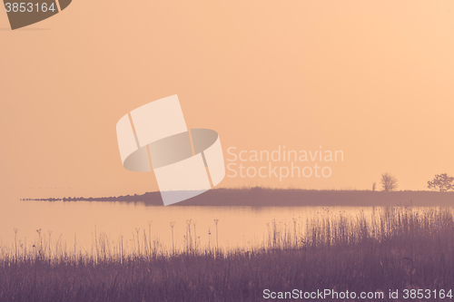 Image of Calm lake in a misty sunrise