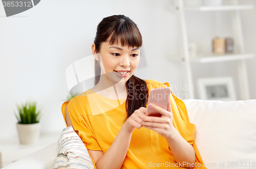 Image of happy asian woman with smartphone at home