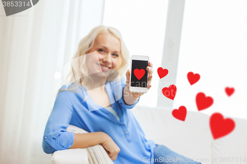 Image of smiling woman with smartphone at home