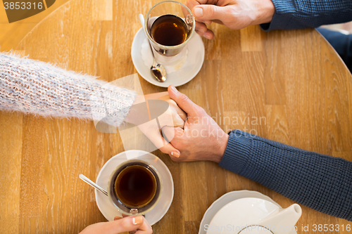 Image of close up of couple holding hands at restaurant