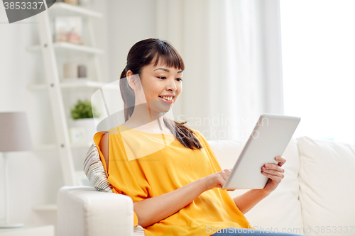 Image of happy young asian woman with tablet pc at home