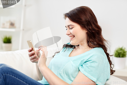 Image of happy plus size woman with smartphone at home