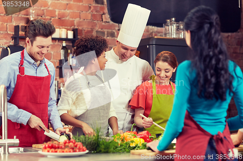 Image of happy friends and chef cook cooking in kitchen