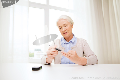 Image of senior woman with glucometer checking blood sugar