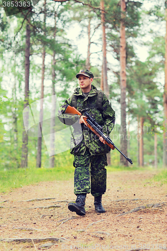 Image of young soldier or hunter with gun in forest