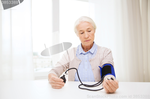 Image of old woman with tonometer checking blood pressure