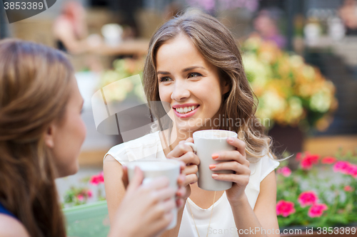 Image of smiling young women with coffee cups at cafe