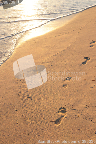 Image of Footprints on sandy beach at sunrise