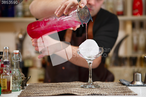 Image of barman pouring a pink cocktail drink 