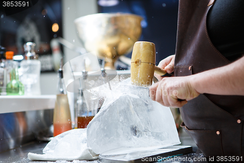Image of Bartender mannually crushed ice with wooden hammer and metal knife.
