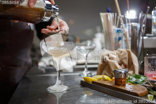 Image of Bartender coocks cocktail behind a bar counter