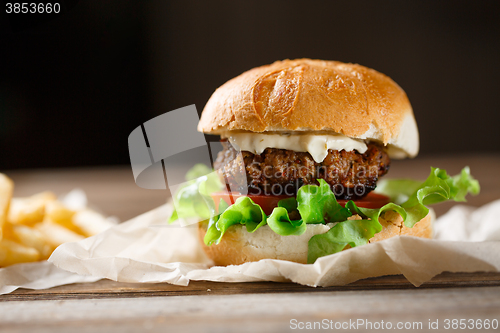 Image of homemade burger and french fries on a wooden plate