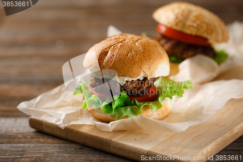 Image of Homemade hamburgers and french fries on wooden table