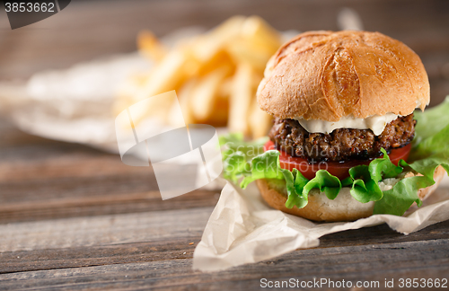 Image of Homemade burger with french fries on wooden table