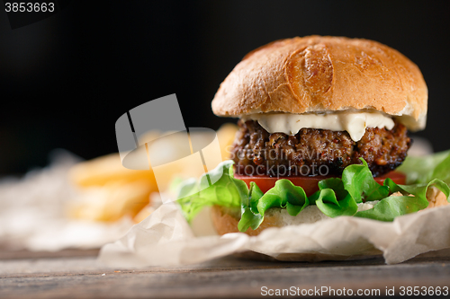 Image of Homemade burger with french fries on wooden table