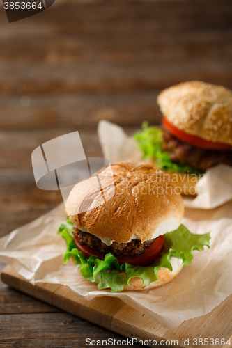 Image of Homemade hamburgers and french fries on wooden table