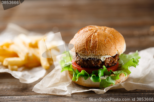 Image of Homemade tasty burger and french fries on wooden table