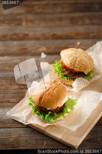 Image of Homemade hamburgers and french fries on wooden table