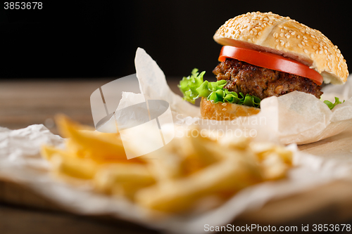 Image of Homemade hamburgers and french fries on wooden table