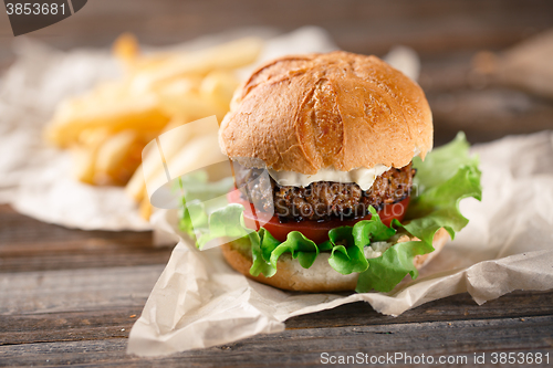 Image of Homemade burger with french fries on wooden table