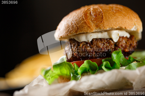 Image of Homemade burger with french fries on wooden table