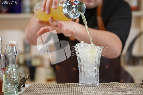 Image of Bartender pouring cocktail into glass at the bar