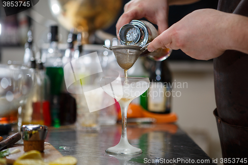 Image of Bartender coocks cocktail behind a bar counter