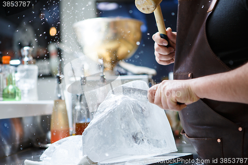 Image of Bartender mannually crushed ice with wooden hammer and metal knife.