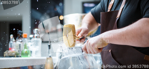 Image of Bartender breaks ice with wooden hammer