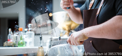 Image of Bartender breaks ice with wooden hammer