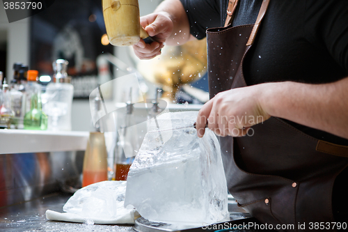 Image of Bartender mannually crushed ice with wooden hammer and metal knife.